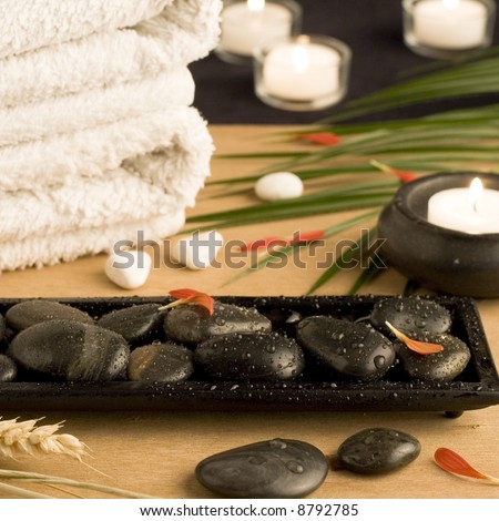 Spa setting with white towels, pebbles, candles and palm leaf