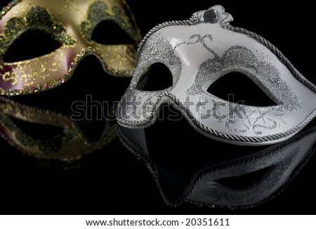 Carnival masks on a black background. The part of masks is reflected by the glass surface