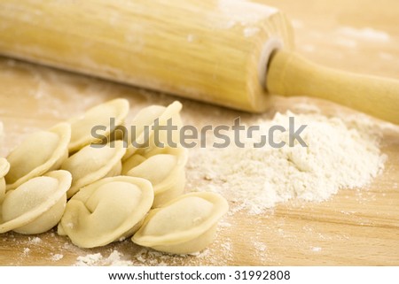 Board with rolling pin, dough and raw pelmeni - Russian traditional speciality