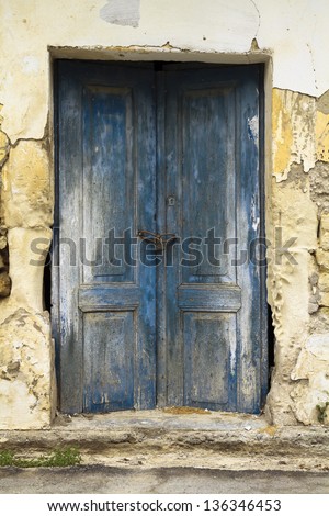 Old ruin with blue double wooden locked doors as building entrance