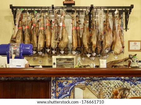 SEVILLE, SPAIN-MAY 9, 2013. Serrano and iberico hamon hanging behind the counter in a small cafe in the centre of Seville. The dry-cured ham is generally served raw in thin slices.