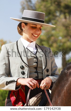 JEREZ DE LA FRONTERA, SPAIN-MAY 12 2013: Female rider decked out in traditional flat-topped hat sitting on her horse smiling during Feria del Caballon, Spains horse fair that lasts for 3 weeks.