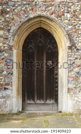 Entrance to an old medieval church in England with strong wooden doors.