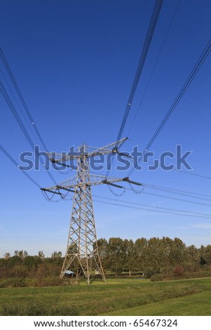 Electricity pylon in perspective against a deep blue sky standing in a green field