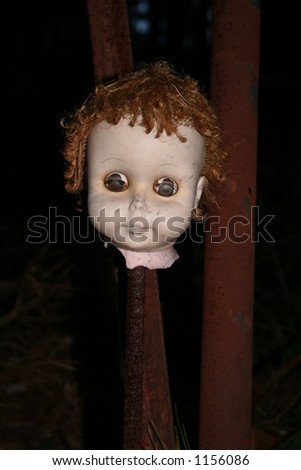 severed creepy doll head on a stake in the woods