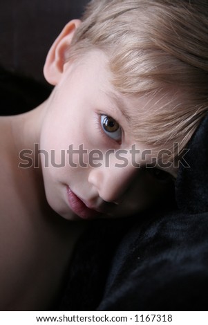 close-up of a little boy\'s face and upper body done on a black background