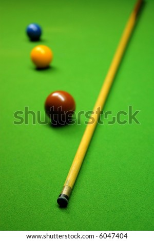 Cue stick and snooker balls over green surface, shallow depth of field