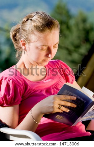 college girl reading a book in the nature