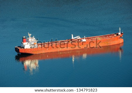 red ship anchoring in a sea inlet