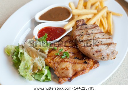 Grilled pork steak and Chicken steak, French fries and vegetables
