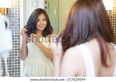 young woman looking at her reflection in the mirror and holding