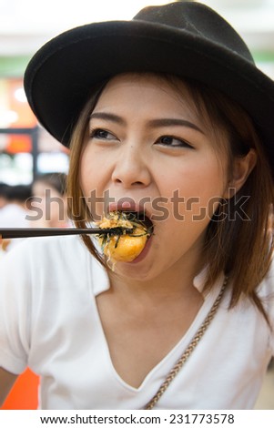 young beautiful asian woman eating sushi with chopsticks