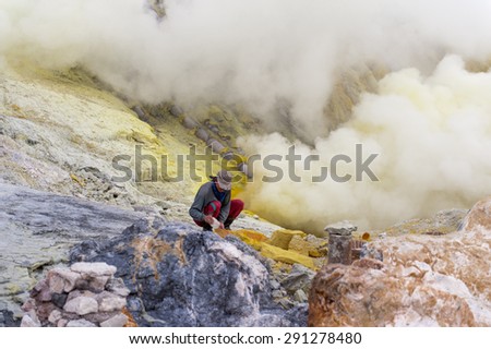 BANYUWANGI, EAST JAVA JULY 20 : Sulphur miner points to hardened sulphur from the ground to be collected and sold on Jul 12, 2013, Ijen volcano, East Java, Indonesia.