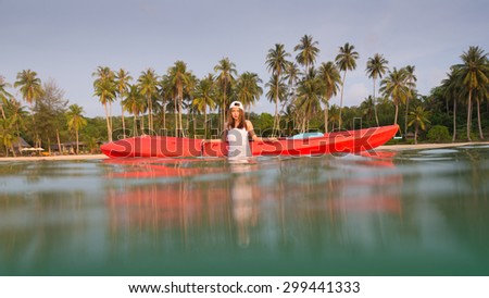 Young lady with the kayak in a tropical lagoon at sunny day