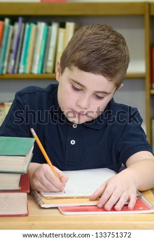 Boy sitting at table in library taking notes for school