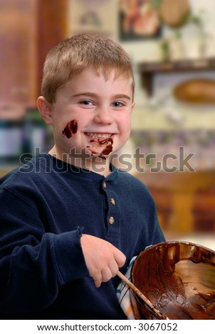 Chocolate drips from happy face of young boy as he scrapes the last of the cake batter from a bowl.