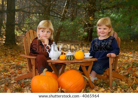 Two young sisters having a tea party in the woods in autumn