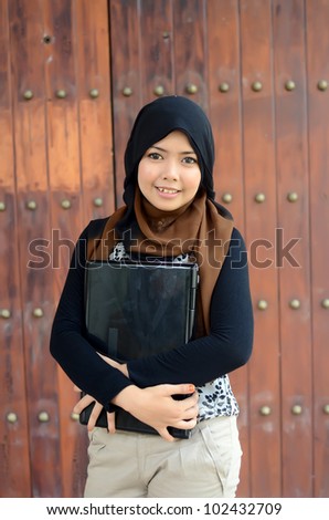 Young Student wearing a veil and holding a notebook with college building on background
