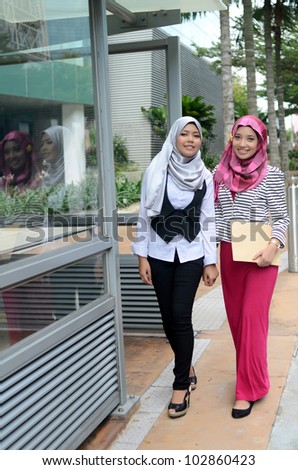 Portrait of pretty young Muslim woman walk together while hold file