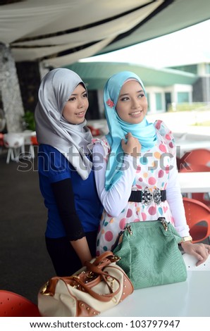 Two young pretty Asian muslim business woman in head scarf with handbag