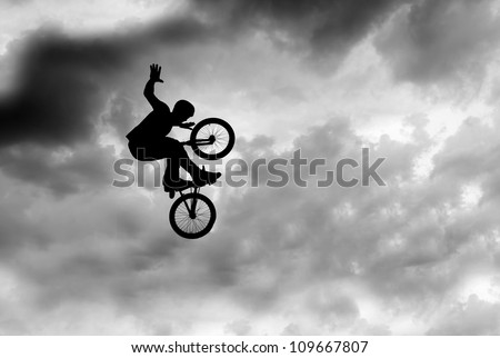 Silhouette of a man doing an extreme jump with a mountain bike .