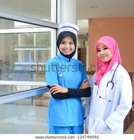 Confident Muslim female doctor and nurse in head scarf smile