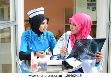 Confident Muslim doctor and nurse busy conversation at hospital