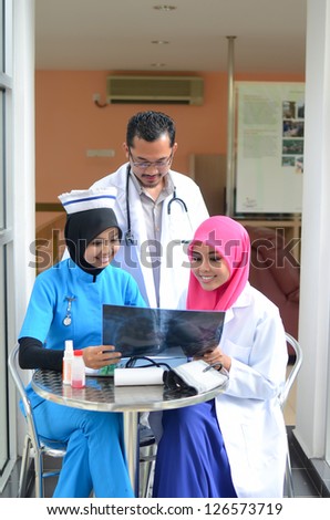 Confident Muslim doctor and nurse busy doctor looking at patient\'s x-ray