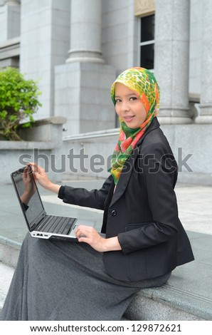 Young asian muslim businesswoman in head scarf smile surf internet