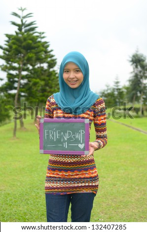 Young asian muslim woman in head scarf smile with friendship board