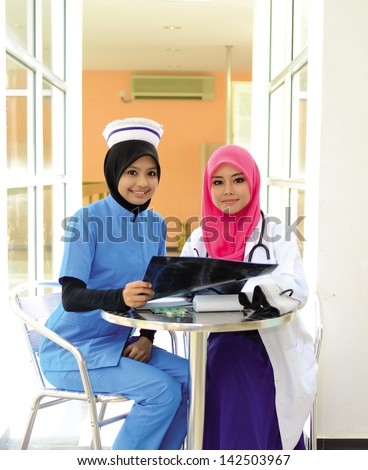 Confident Muslim female doctor and nurse in head scarf smile