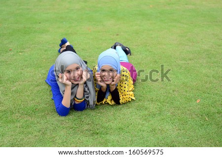 Young muslim girl wearing hijab lying on grass