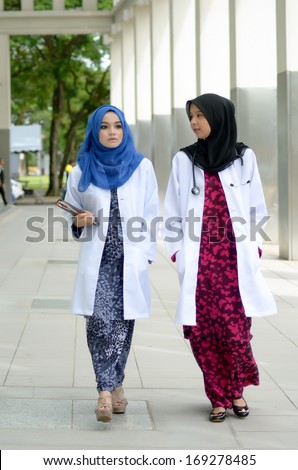 Young asian muslim confident medical doctor walking to hospital