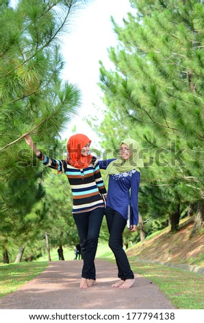 Two young Muslim women with notebook while relaxing in the park