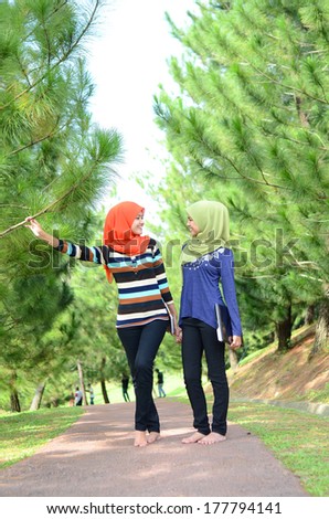 Two young Muslim women with notebook while relaxing in the park