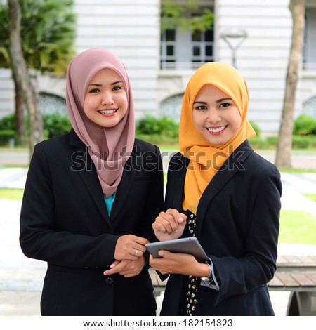 Image of two young businesswomen using touchpad outdoor meeting