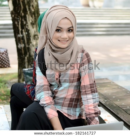 Young asian muslim woman in head scarf smile while sitting with friend