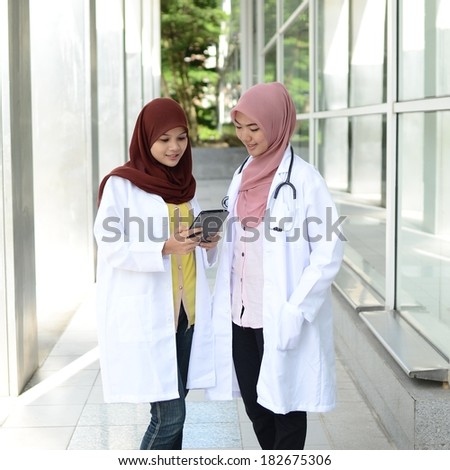 Confident Muslim medical student busy conversation using touchpad pc