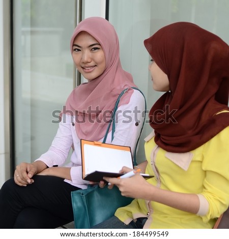 Two young Muslim women with notebook