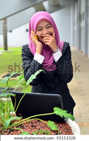 Portrait of beautiful young Asian Muslim business woman happy talking on the mobile phone