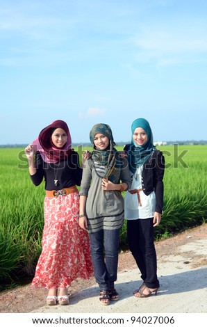 three young pretty Asian muslim college girl at green paddy field