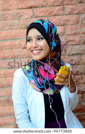 young pretty Asian muslim college girl with listen to music.