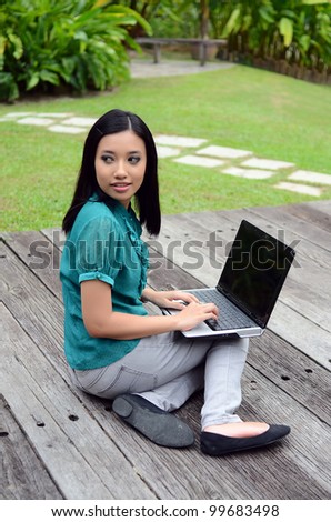 Portrait of beautiful woman in park garden working on laptop computer