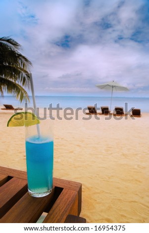 A blue drinks stands against a caribbean beach