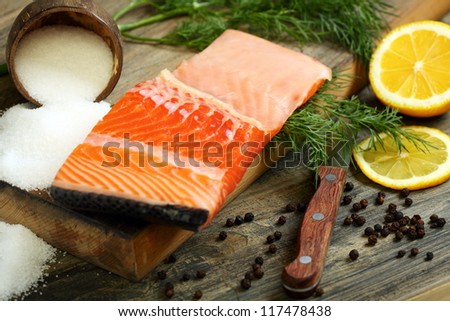Fresh salmon with dill and lemon on a wooden table.