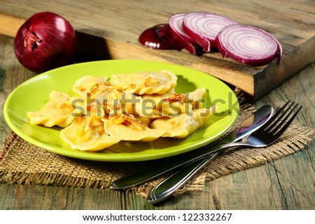 Dumplings with cabbage and red onions on a wooden table.