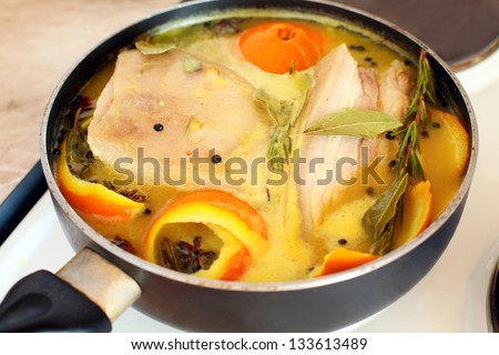 Pork loin in orange juice with spices cooked in a skillet.
