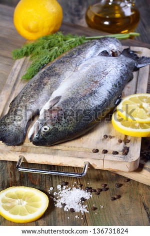 Trout on cutting board, lemon and a bottle of oil.