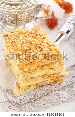 Silver blade with a cake of puff pastry on a linen napkin.