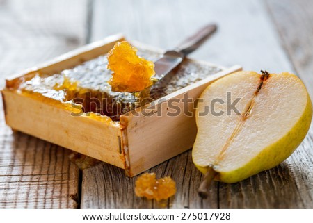 Honey comb, knife and a slice of pear on an old table.